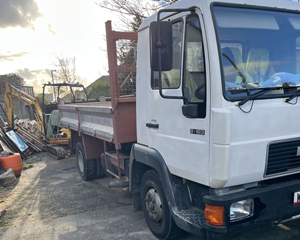 white truck parked in a construction area with excavators and materials visible in the background suitable for transporting
